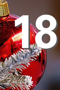 Rote Christbaumkugel mit schneebedecktem Tannenzweig und weiße Zahl "18" im Vordergrund.