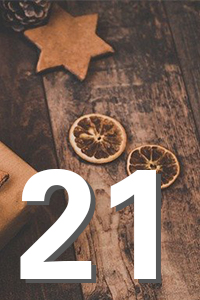 Große weiße Zahl "21" über rustikalem Holzhintergrund mit getrockneten Orangenscheiben und einem sternförmigen Keks.