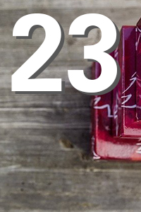 Große weiße Zahl "23" über einem unscharfen Holzhintergrund; rechts teilweise sichtbar ein roter, glänzender Kerzenhalter.