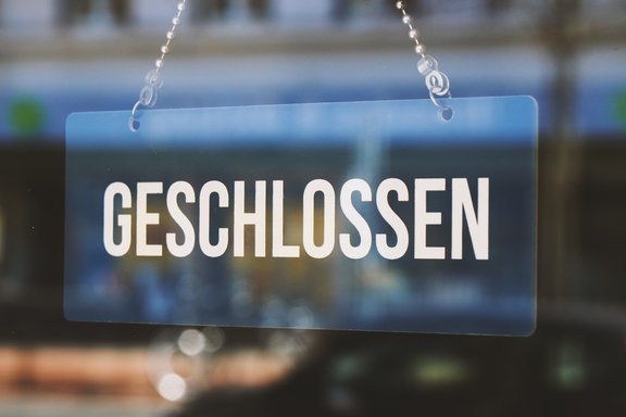 Ein Schild mit der Aufschrift geschlossen hängt an einem Fenster.