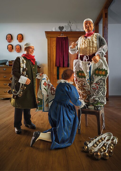 Drei Personen in historischen Uniformen und Kleidung posieren vor einem Regal mit Puppen. (KI generiert)