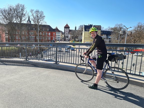 Fahrradfahrer vor einem grauen Geländer. Im Hintergrund sieht man das Bickentor von Villingen.