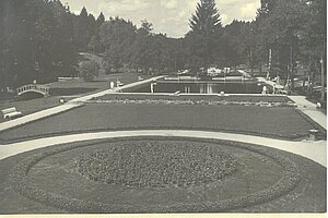 Parkanlage des Kneipp-Kurorts Villingen: vorn kreisförmige Blumenrabatten, dahinter symmetrische rechteckige Becken mit Gehwegen, Bänken und umgebenden Bäumen.