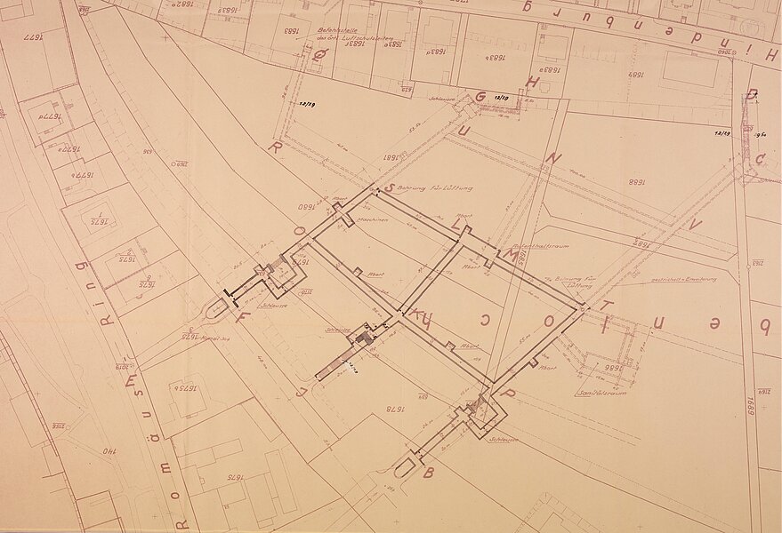 Lageplan eines Gebäudekomplexes: Grundrisse dreier verbundener rechteckiger Baukörper, Verbindungswände, umgebende Parzellen, Straßenverläufe und Maßangaben.