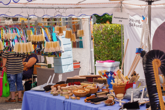 Marktstand mit großer Auswahl an Hand- und Reinigungsbürsten aus Holz und Naturborsten, auf Tischen und hängend präsentiert.