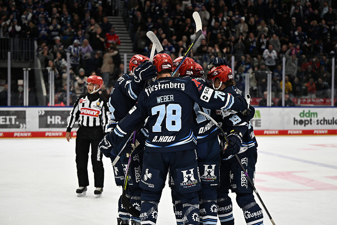 Spieler der Schwenninger Wild Wings jubeln gemeinsam auf dem Eis der Helios Arena, im Hintergrund die Fans