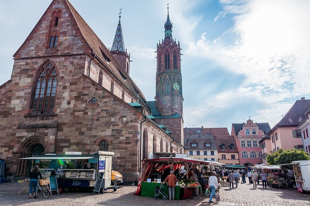 Historische Kirche mit Marktplatz und bunten Häusern. (KI generiert)
