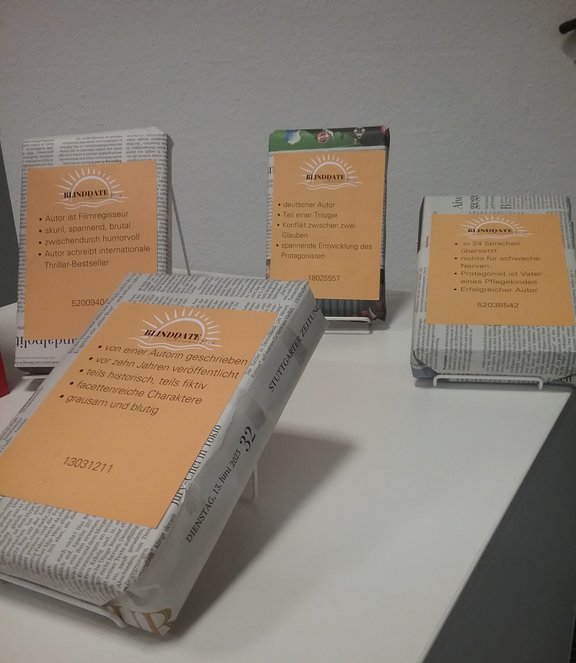 Vier Bücher in Zeitungspapier verpackt. Man erkennt einen Aufdruck auf den Büchern mit einigen Fakten über die Bücher.