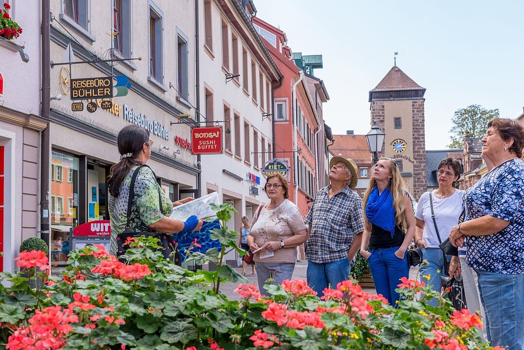Eine Gruppe von Touristen auf einer Stadtführung in einer malerischen Altstadt. (KI generiert)