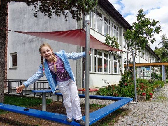Eine Schülerin spielt vor dem Gebäude der Grundschule.