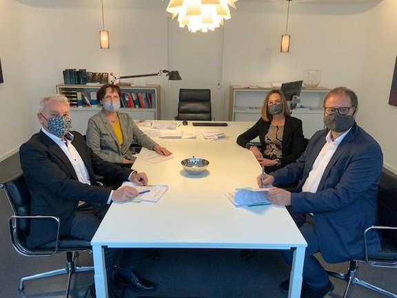 Markus Kästel und Astrid Dülfer von der BImA sitzen an einem Tisch Oberbürgermeister Jürgen Roth und Rechtsamtsleiterin Karin Feger gegenüber. Es zeigt sie beim Notartermin. 