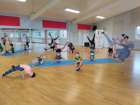 Eine Breakdance-Gruppe in verschidensten Position von einem einarmigen Handstand bis hin zu einem sich drehenden Kopfstand