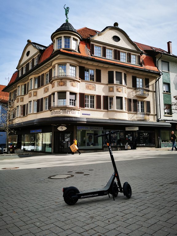 Ein E-Tretroller steht in der Schwenninger Innenstadt. Im Hintergrund wird ein Haus von der Sonne angestrahlt.