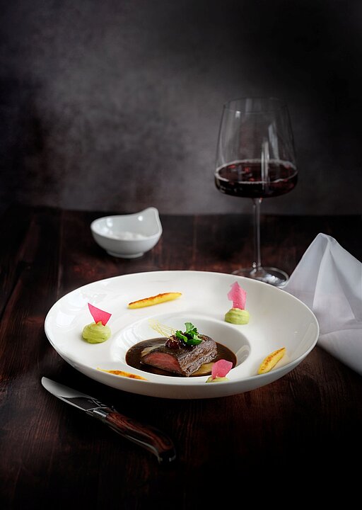 Teller mit Sushi, Sojasauce und Stäbchen auf dunklem Tisch, daneben Glas Wasser. (KI generiert)